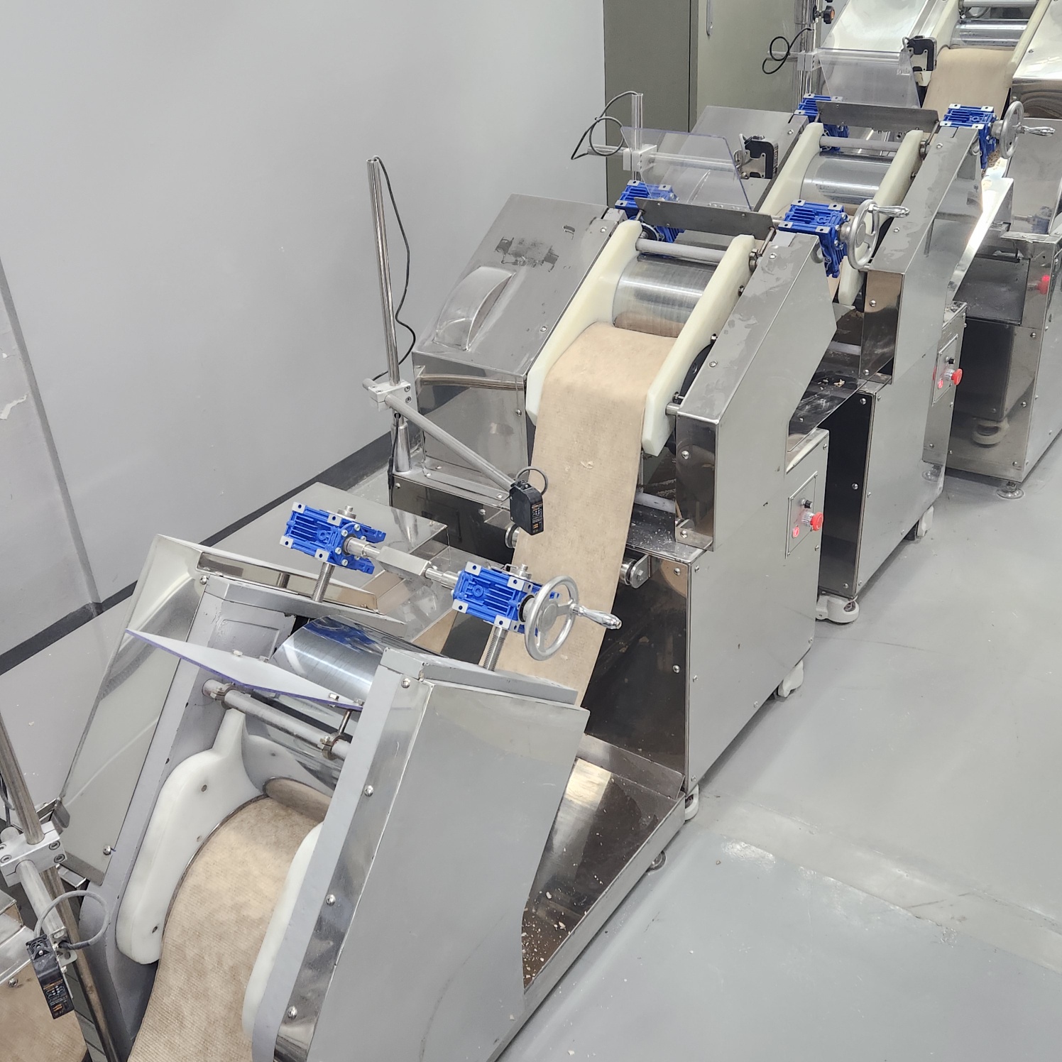Detail of stainless steel dough processing machinery with adjustment controls